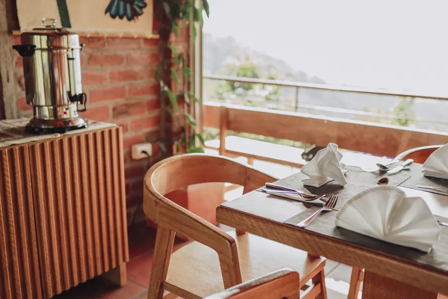 El comedor del lodge, con las mesas puestas junto a ventanas abiertas hacia los Llanganates