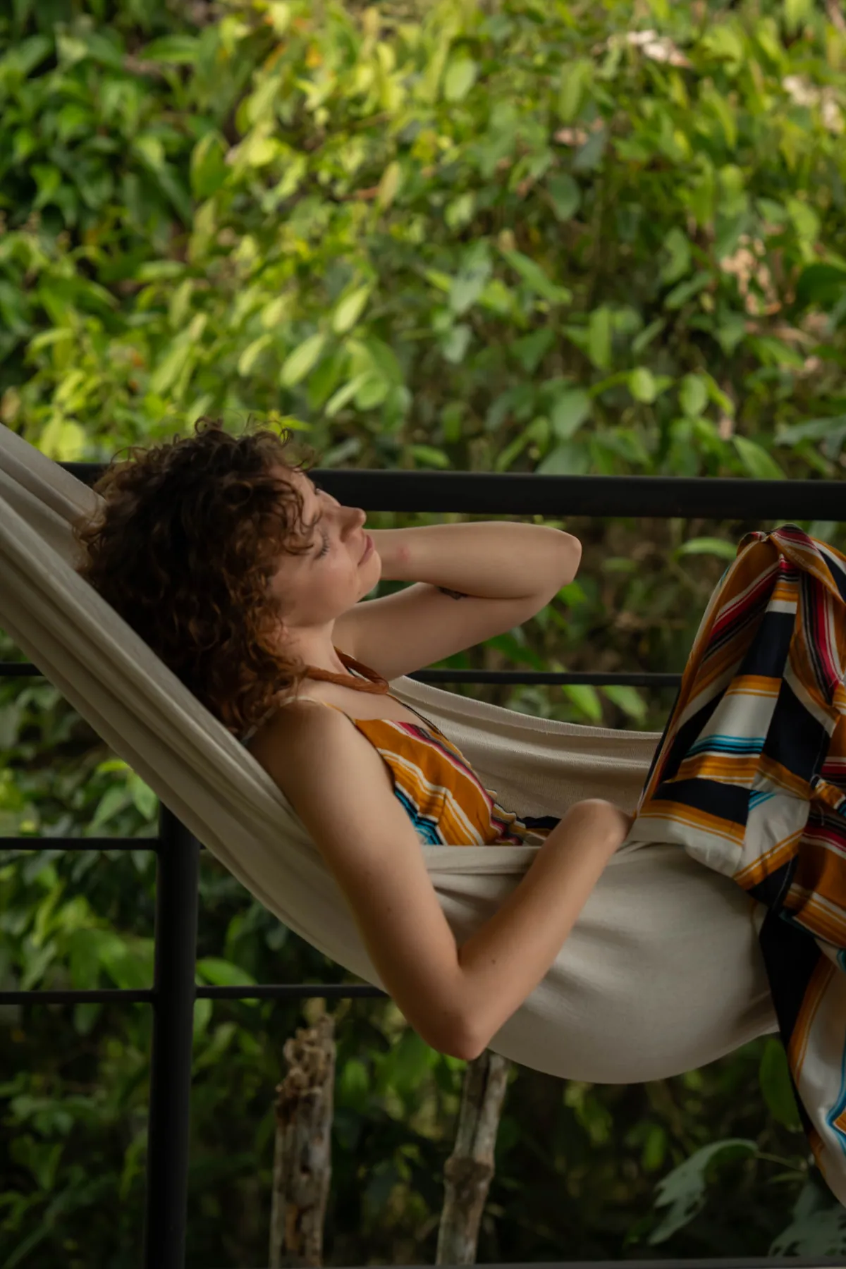 A guest lying back in the Sky Hammock, strung above the forest, her eyes closed